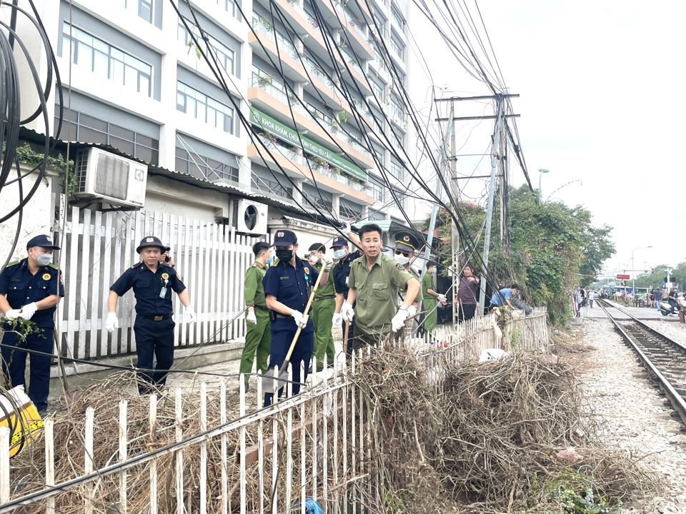 C&aacute;c lực lượng phối hợp dọn dẹp vệ sinh tại khu vực h&agrave;ng r&agrave;o s&aacute;t đường sắt tại Cổng 3 đến Cổng 4 tại Bệnh viện Bạch Mai.