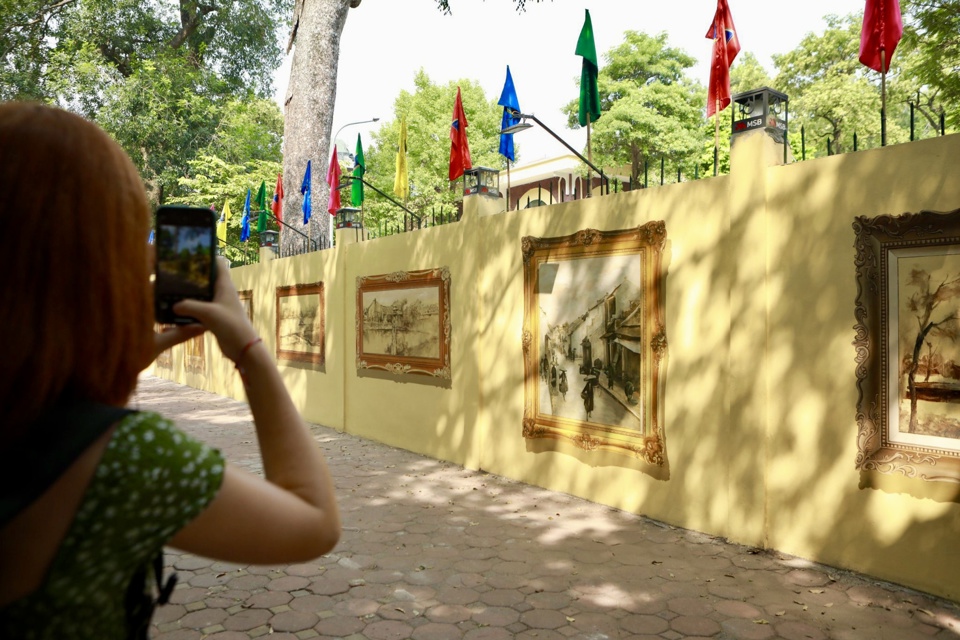 Một du khách nước ngoài thích thú chụp lại những bức tranh bích hoạ 3D về Hà Nội làm kỷ niệm.