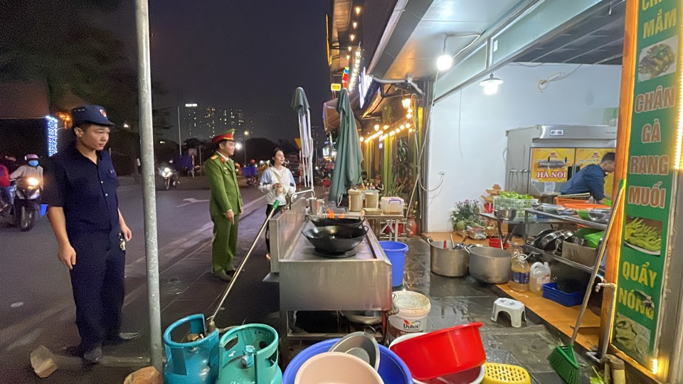 Lực lượng chức năng phường Phú Đô kiểm tra, nhắc nhở các hộ kinh doanh lấn chiếm vỉa hè làm nơi kinh doanh trên phố Hồng Đô. Ảnh: Công Trình