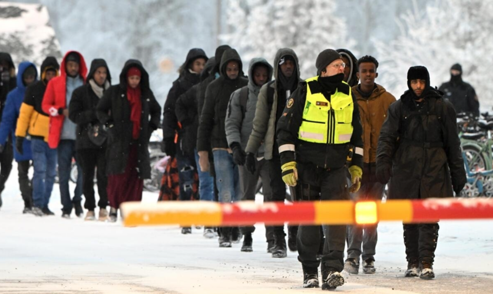 Một nh&acirc;n vi&ecirc;n bi&ecirc;n ph&ograve;ng Phần Lan hộ tống người di cư ở bi&ecirc;n giới với Nga. Ảnh: AFP