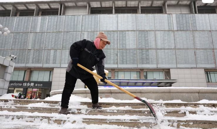 Một c&ocirc;ng nh&acirc;n x&uacute;c tuyết ph&iacute;a trước trung t&acirc;m thương mại khi tuyết rơi d&agrave;y ở Bắc Kinh ng&agrave;y 14/12. Ảnh: Reuters
