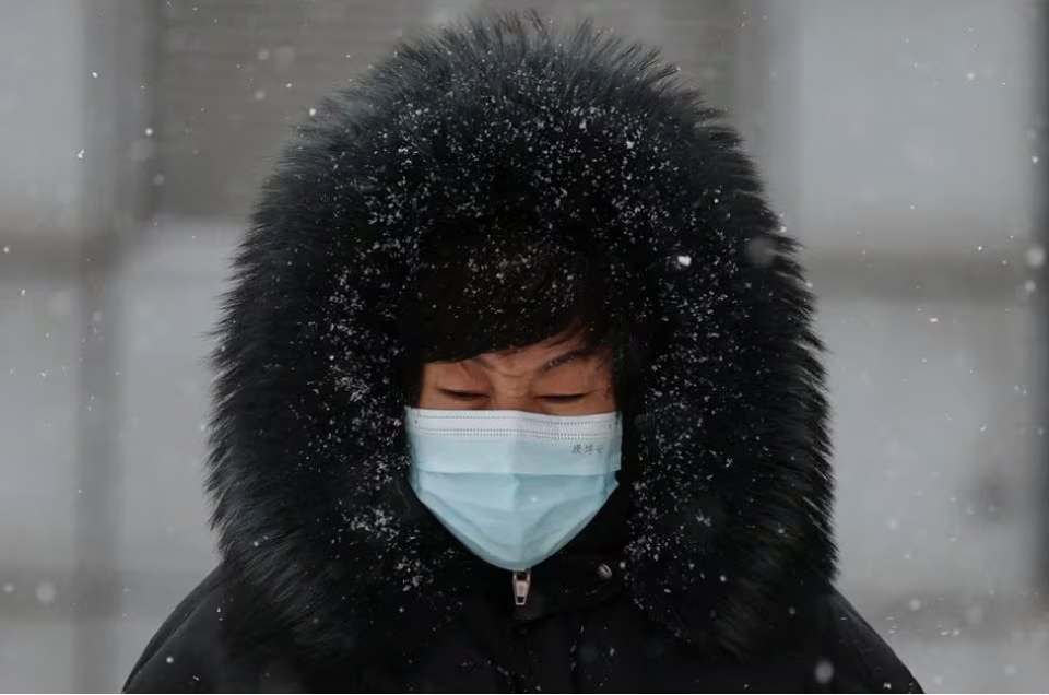 Người phụ nữ Trung Quốc phải mặc rất nhiều đồ ấm khi đi bộ tr&ecirc;n đường v&igrave; tuyết rơi v&agrave; lạnh s&acirc;u trong ng&agrave;y 14/12. Ảnh: Reuters