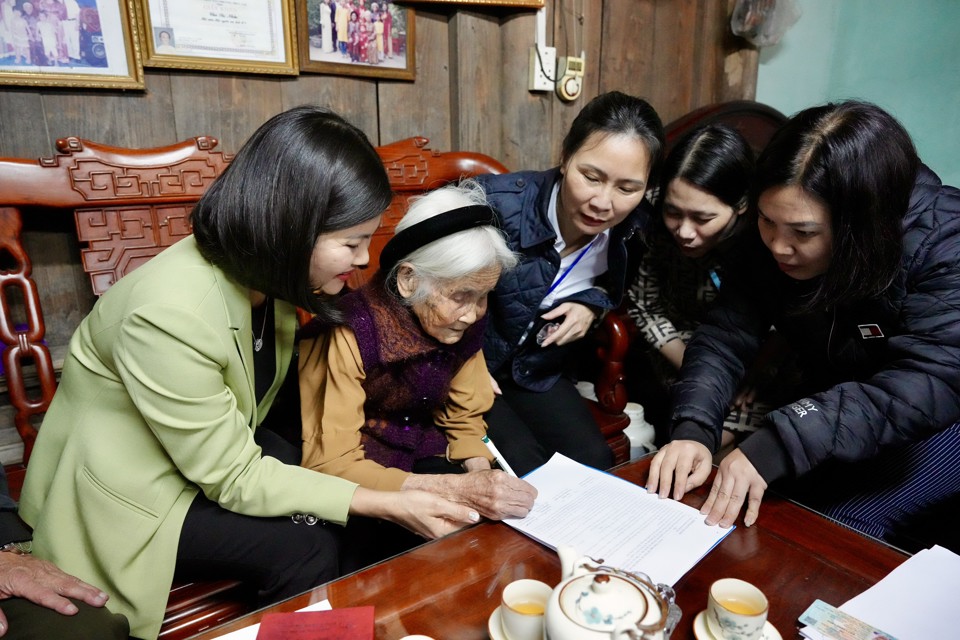 Phó Chủ tịch UBND quận Long Biên Đinh Thị Thu Hương (ngoài cùng bên trái) đến nhà cụ Chu Thị Nhớn (99 tuổi) phường Phúc Lợi mở tài khoản chi trả trợ cấp. Ảnh: Duy Khánh