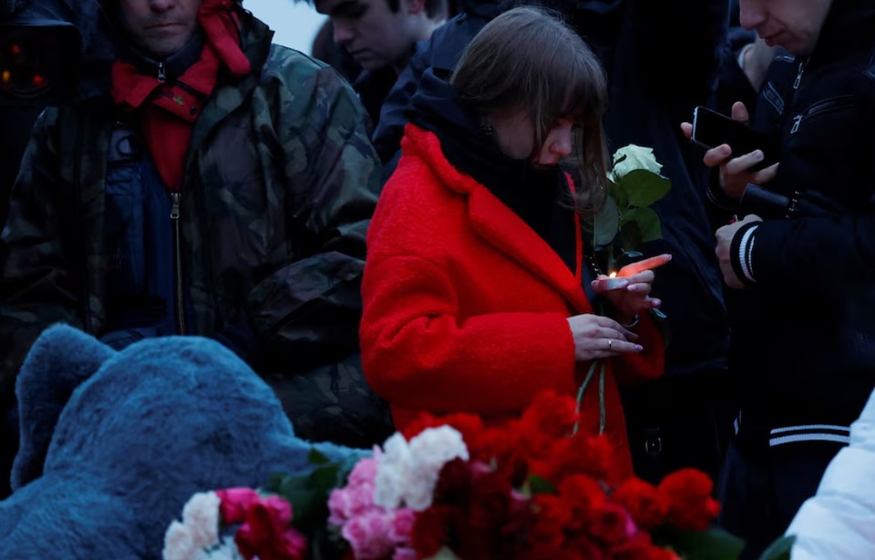 Một người phụ nữ cầm nến tại đ&agrave;i tưởng niệm tạm thời tưởng nhớ c&aacute;c nạn nh&acirc;n của vụ tấn c&ocirc;ng nổ s&uacute;ng được dựng b&ecirc;n ngo&agrave;i nh&agrave; h&aacute;t Crocus ở Moscow, Nga, ng&agrave;y 23/3/2024. Ảnh: Reuters