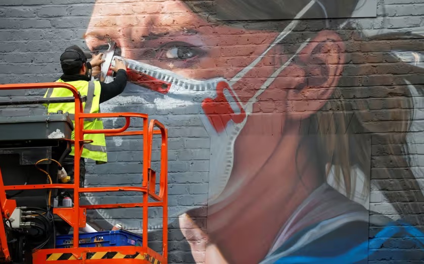 Một nghệ sĩ đang vẽ tranh tường trong đại dịch Covid-19 ở Manchester. Một số nh&agrave; khoa học tin rằng Sars-Cov-2 vẫn l&agrave; một mối đe dọa. Ảnh: Reuters