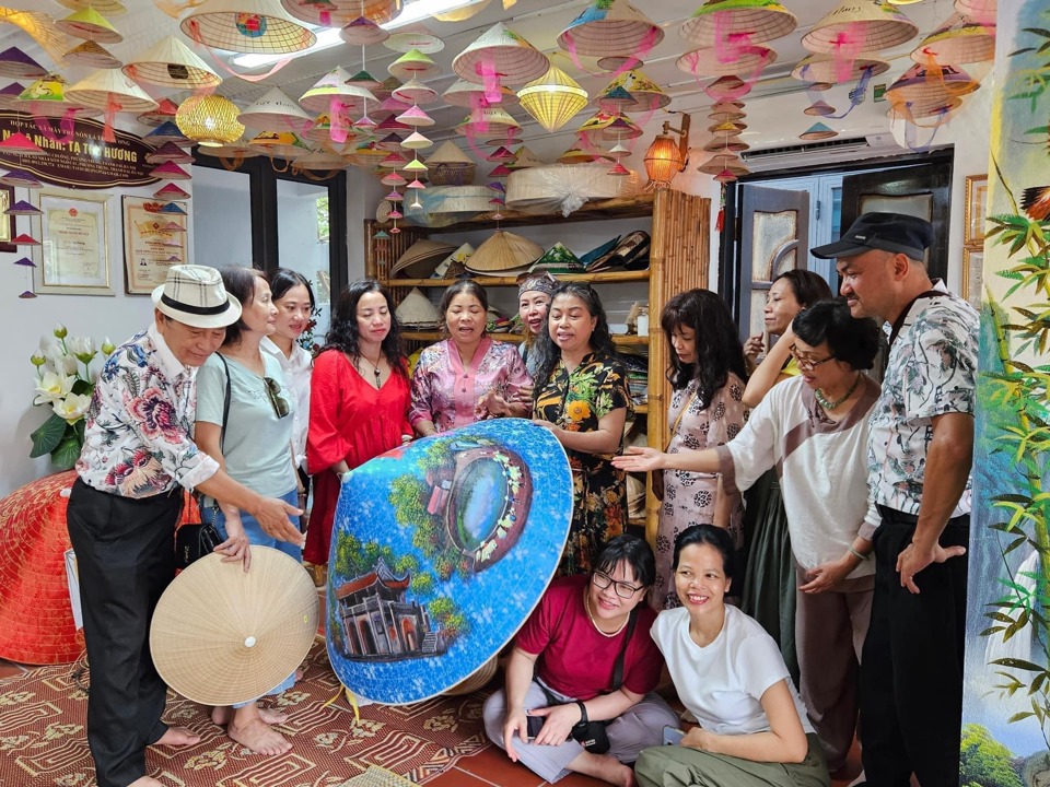 Khách du lịch tham quan, chụp ảnh lưu niệm tại một cơ sở sản xuất nón lá làng Chuông, huyệnThanh Oai. Ảnh:Ngọc Ánh
