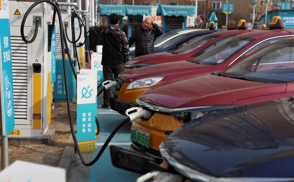 Caacute;c tagrave;i xế trograve; chuyện becirc;n cạnh những chiếc taxi điện tại trạm sạc Shell ở Bắc Kinh, Trung Quốc, ngagrave;y 2/2/2024. Ảnh: Reuters