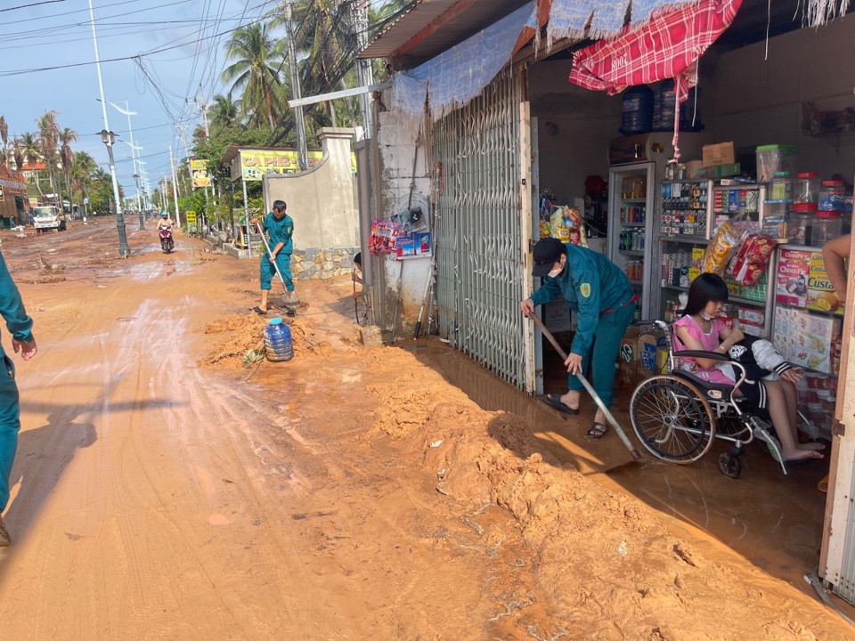 Lực lượng trật tự d&acirc;n phố gi&uacute;p c&aacute;c hộ d&acirc;n dọn dẹp b&ugrave;n c&aacute;t.