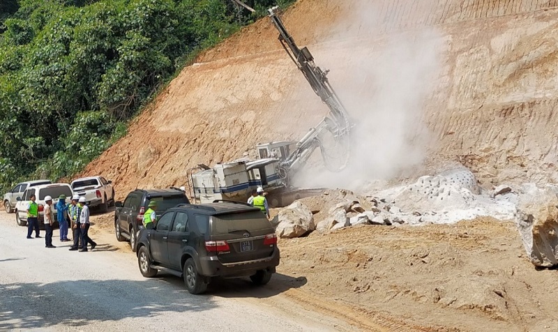 Đại diện chủ đầu tư cho biết, qu&aacute; tr&igrave;nh thi c&ocirc;ng&nbsp;Quốc lộ 8A đ&atilde; gặp phải những khối đ&aacute; rất lớn, cường độ tr&ecirc;n 100MPa (đ&aacute; cứng C1) . Trong đ&oacute; ri&ecirc;ng g&oacute;i thầu XL9 c&oacute; hơn 3.500m3 đ&aacute; ở 5 điểm lớn. Đ&acirc;y&nbsp;l&agrave; tuyến đường độc đạo, lưu lượng xe tải lớn, c&oacute; t&iacute;nh chất an ninh quốc ph&ograve;ng quan trọng, c&aacute;c đường d&acirc;y điện 110KV, 35KV đi gần tuyến n&ecirc;n việc nổ m&igrave;n kh&ocirc;ng đảm bảo an to&agrave;n. V&igrave; vậy, giải ph&aacute;p khoan đ&aacute; tiếp tục được chủ đầu tư v&agrave; c&aacute;c đơn vị thi c&ocirc;ng gấp r&uacute;t thực hiện, g&oacute;p phần th&uacute;c đẩy nhanh tiến độ dự &aacute;n