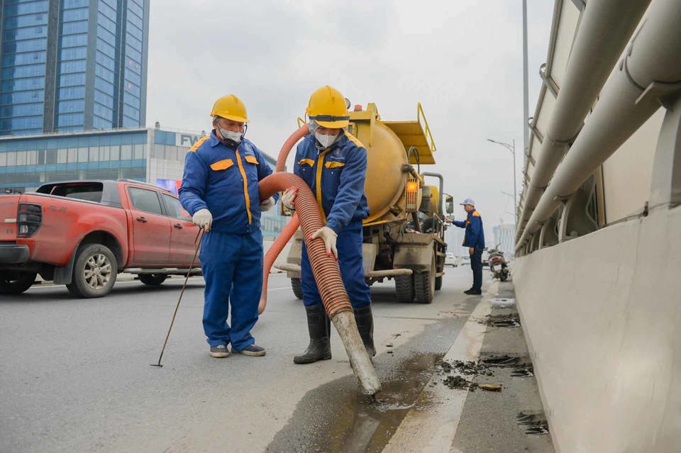 Công nhân Xí nghiệp quản lý công trình giao thông số 3 dọn phế thải, xử lý đất, cát,rác thải trên đườngVành đai 2 trên cao đoạn từ Ngã Tư Sở tới Ngã TưVọng. Ảnh: Ngọc Tuấn