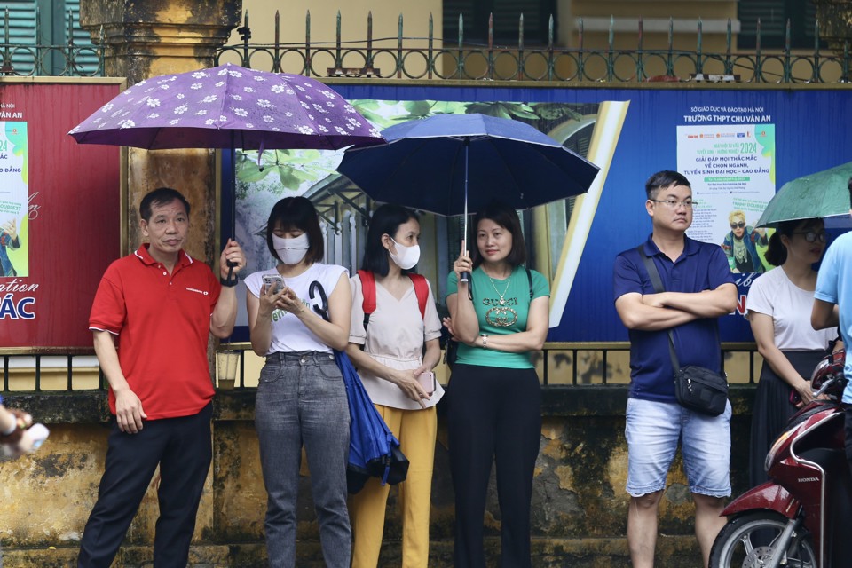Phụ huynh đội mưa chờ đ&oacute;n con ở cổng điểm thi Trường THPT Chu Văn An.Ảnh Duy Kh&aacute;nh