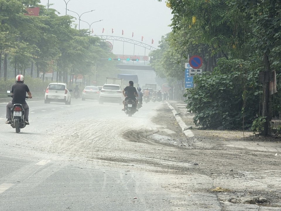 Một đoạn tr&ecirc;n Quốc lộ 32 bụi tung m&ugrave; mịt do b&ugrave;n đất từ c&ocirc;ng trường gần đ&oacute; g&acirc;y ra. Ảnh: Nguyễn Qu&yacute;