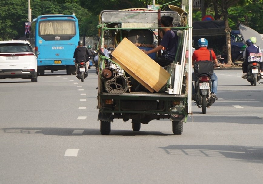 Một em nhỏ ngồi sau th&ugrave;ng xe giữ đồ giữa thời tiết nắng n&oacute;ng đầy nguy hiểm.