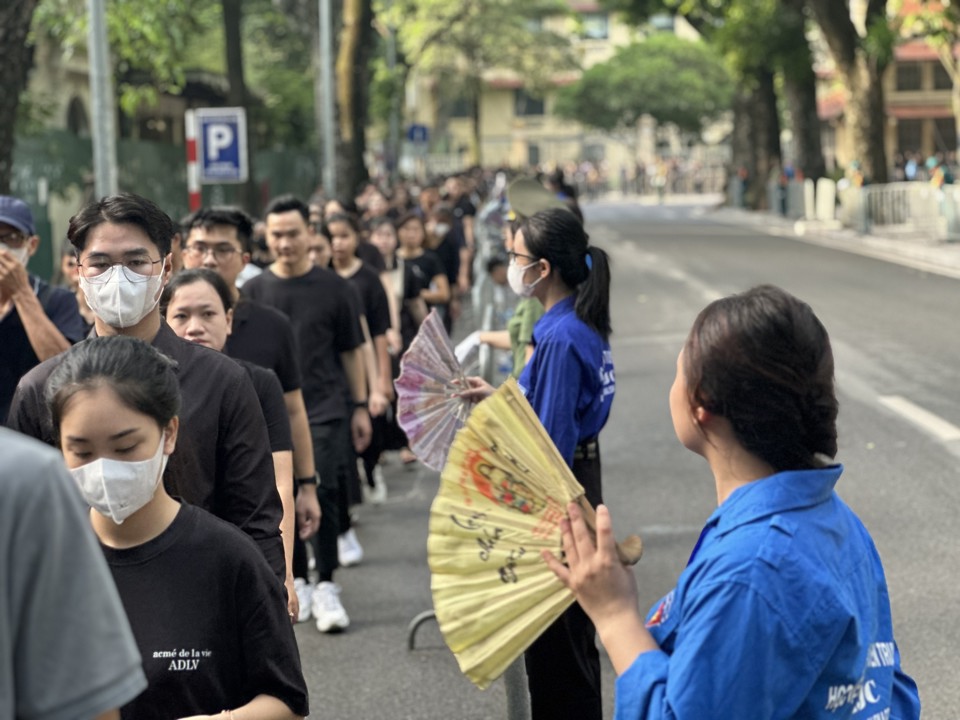 Thanh ni&ecirc;n t&igrave;nh nguyện đ&atilde; tạo luồng gi&oacute; m&aacute;t bằng những chiếc quạt tay để người d&acirc;n v&agrave;o viếng được m&aacute;t hơn