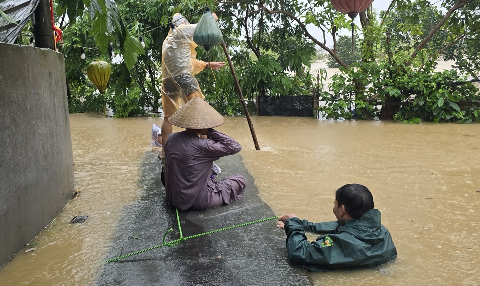 Lực lượng chức năng phường Ph&uacute; Thượng đội mưa, ng&acirc;m m&igrave;nh trong nước di chuyển người d&acirc;n khu vực ngập lụt đến nơi an to&agrave;n.