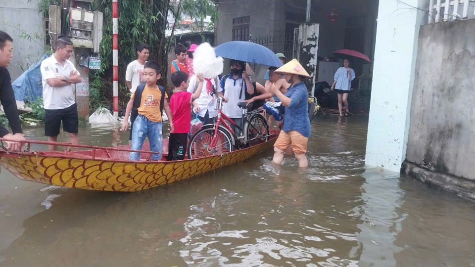 Phụ huynh tại x&atilde; Ph&uacute; Kim đưa con em đi học bằng thuyền qua khu ngập &uacute;ng. Ảnh: N.M.