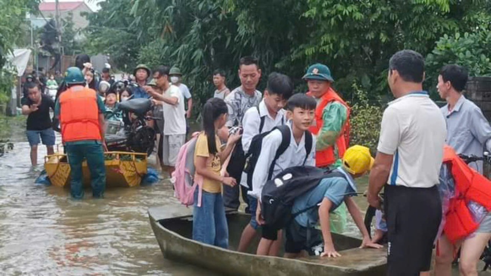 Lực lượng chức năng v&agrave; người d&acirc;n hỗ trợ đưa học sinh qua khu ngập để đến trường. Ảnh: N.M.