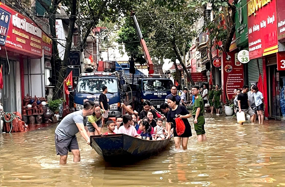 Người d&acirc;n khu vực ven s&ocirc;ng Hồng, huyện Gia L&acirc;m được thuyền cứu hộ của huyện Mỹ Đức gi&uacute;p di chuyển ra khỏi v&ugrave;ng lũ.