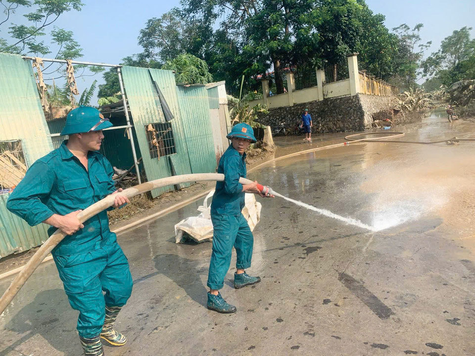 Lực lượng d&acirc;n qu&acirc;n tự vệ x&atilde; Trung Ch&acirc;u sử dụng m&aacute;y bơm c&ocirc;ng suất lớn xịt rửa b&ugrave;n đất đọng lại tr&ecirc;n c&aacute;c tuyến đường sau khi nước lũ r&uacute;t.