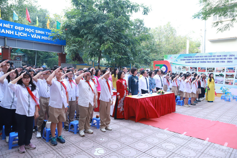 C&aacute;c đại biểu, thầy c&ocirc; v&agrave; học sinh to&agrave;n trường thực hiện nghi thức Ch&agrave;o cờ.