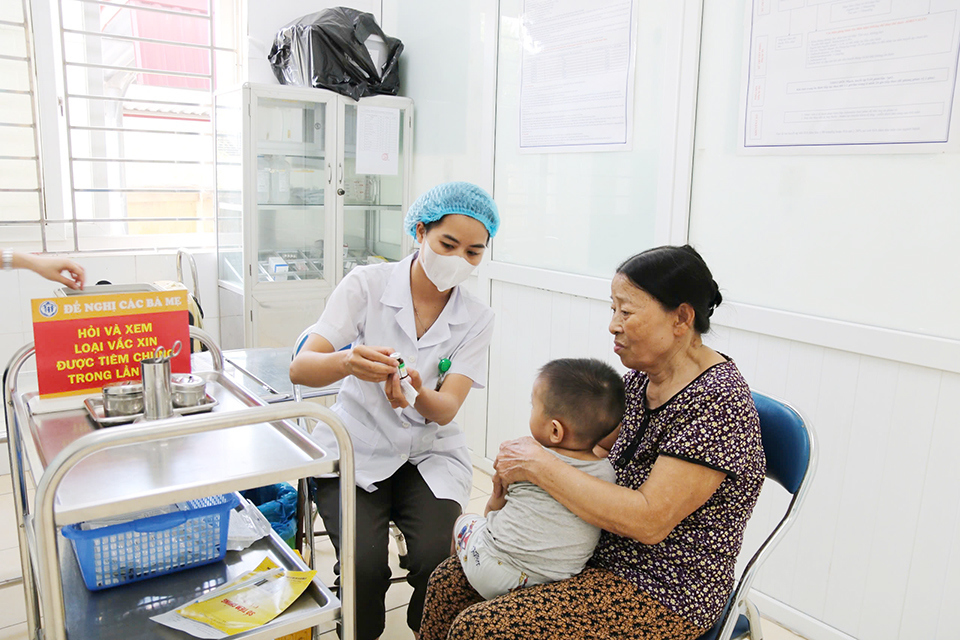 C&aacute;n bộ y tế TYT x&atilde; Minh Cường, huyện Thường T&iacute;n th&ocirc;ng tin cho gia đ&igrave;nh về loại vaccine được sử dụng để ti&ecirc;m ph&ograve;ng cho trẻ trước khi ti&ecirc;m.