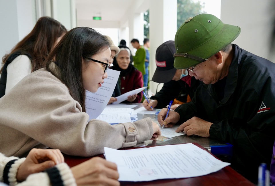 Hỗ trợ người cao tuổi làm thủ tục mở tài khoản nhận chi trả tiền tiền trợ cấp hàng tháng tại phường Giang Biên, quận Long Biên. Ảnh: Thanh Hải