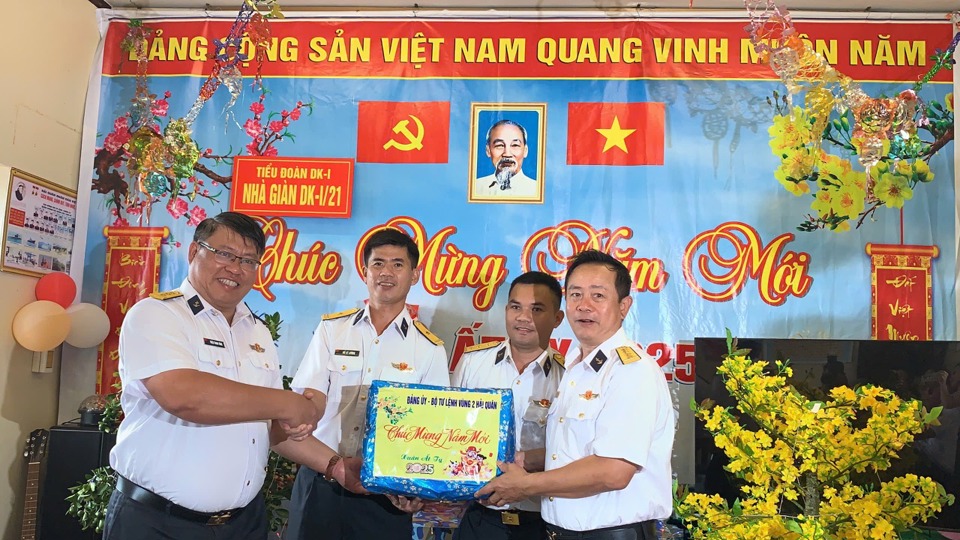 Đại t&aacute; Vũ Duy Lưu, Ph&oacute; Chủ nhiệm ch&iacute;nh trị, Bộ Tư lệnh V&ugrave;ng 2 hải qu&acirc;n (ngo&agrave;i c&ugrave;ng b&ecirc;n phải) v&agrave;&nbsp;Thượng t&aacute; Triệu Thanh T&ugrave;ng, Trưởng đo&agrave;n c&ocirc;ng t&aacute;c t&agrave;u Trường Sa 21 (ngo&agrave;i c&ugrave;ng b&ecirc;n tr&aacute;i) trao qu&agrave; Tết tới c&aacute;n bộ, chiến sĩ Nh&agrave; gi&agrave;n DKI/21 - Ảnh: V&acirc;n H&agrave;