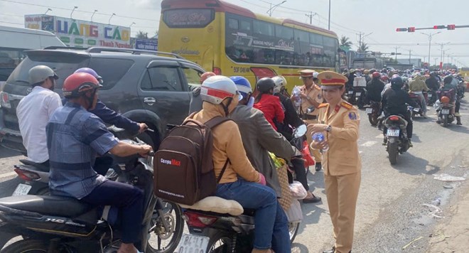 Lực lượng Cảnh s&aacute;t giao th&ocirc;ng thuộc Ph&ograve;ng CSGT C&ocirc;ng an tỉnh Tiền Giang ph&aacute;t nước miễn ph&iacute; cho người d&acirc;n về qu&ecirc; tr&ecirc;n Quốc lộ 1. Ảnh: Th&agrave;nh Nh&acirc;n