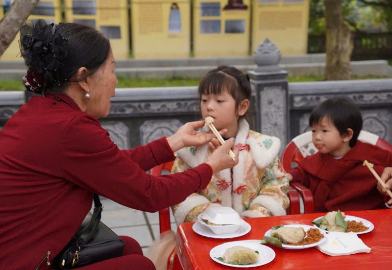 C&aacute;c em nhỏ rất th&iacute;ch th&uacute; khi ăn b&aacute;nh chưng tại lễ hội